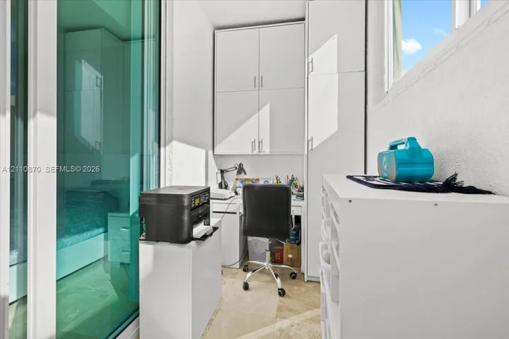 Built-in floor-to-ceiling white cabinetry, tile flooring, and sliding glass panel door