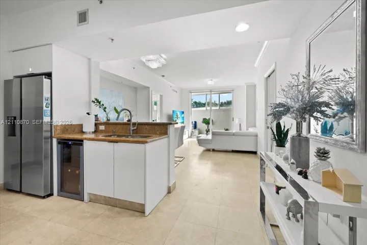 Kitchen area featuring stone-finish countertops, stainless steel side-by-side refrigerator, under-counter wine cooler, and tile flooring