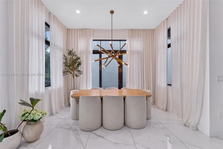 Large-format stone tile flooring, floor-to-ceiling drapery, multi-paned windows, and a multi-arm metallic chandelier
