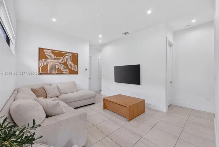 Neutral-toned large-format tile flooring, recessed ceiling lighting, and smooth-finish walls