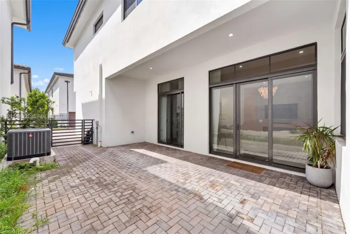 Covered patio featuring brick pavers, recessed ceiling lighting, and large sliding glass doors with transom windows