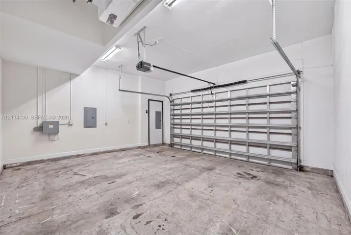 Multi-car garage featuring a concrete floor, sectional roll-up door, automated garage door opener, and integrated overhead lighting