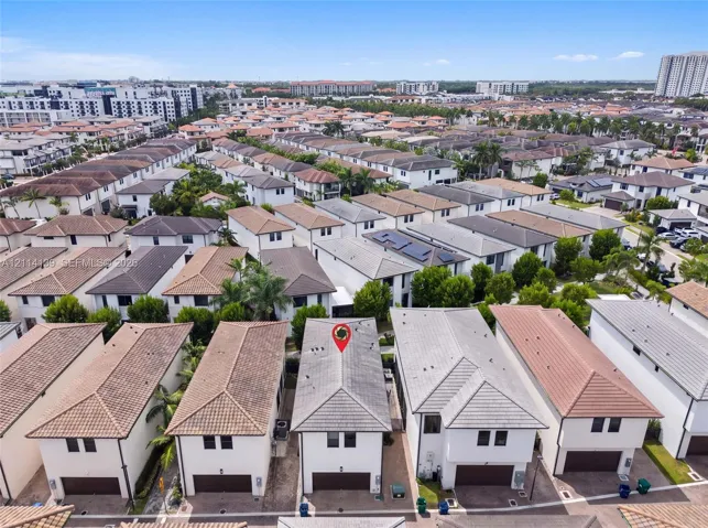 Aerial perspective of a multi-story residence featuring a hipped tile roof, white stucco exterior, integrated garage, and a compact private lot