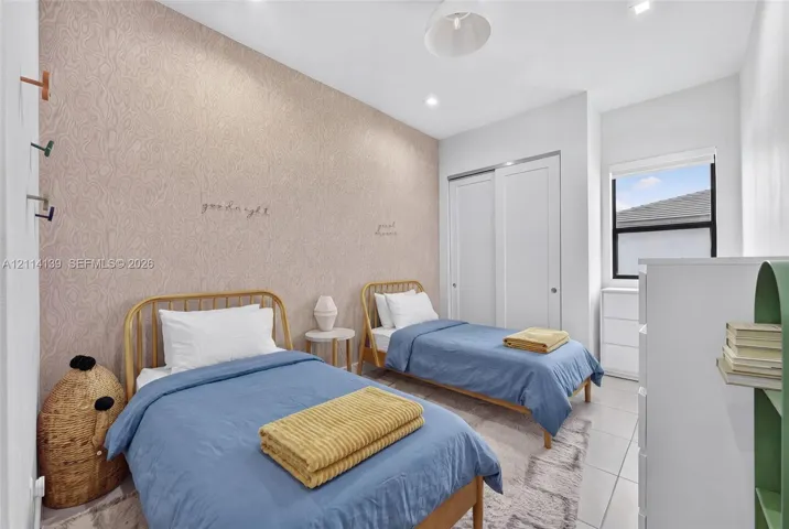 Neutral-toned bedroom featuring patterned wallpaper, tile flooring, recessed lighting, and a sliding-door closet