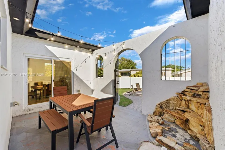 Enclosed courtyard featuring a stone-accented water feature, arched architectural openings, integrated string lighting, and herringbone-patterned stone paver flooring