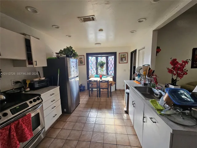 Kitchen featuring tile flooring, white cabinetry, recessed lighting, stainless steel appliances, and a leaded-glass bay window