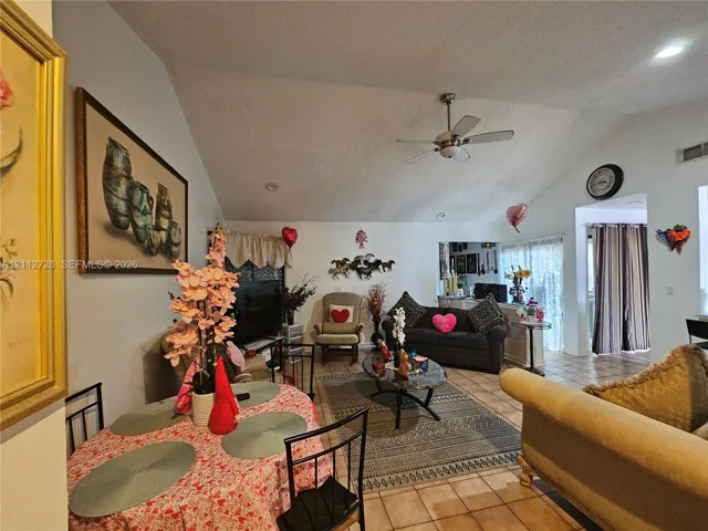 Vaulted ceilings with a ceiling fan, neutral wall finishes, and tile flooring