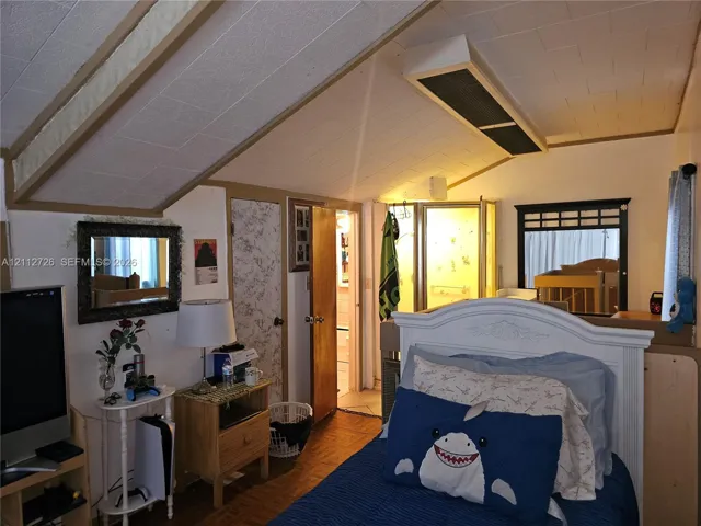Vaulted ceiling with exposed beams, wood-finish flooring, and enclosed shower stall