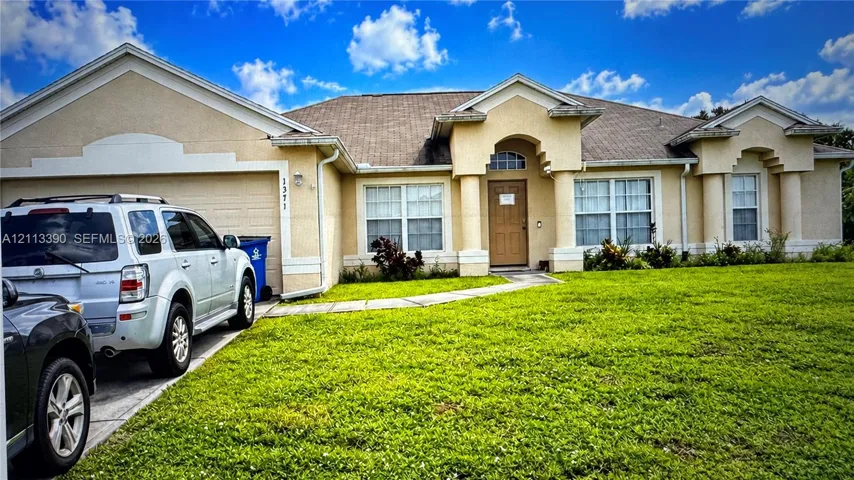 Single-story exterior featuring a stucco facade, multi-gabled roofline, columned entryway, and a concrete driveway