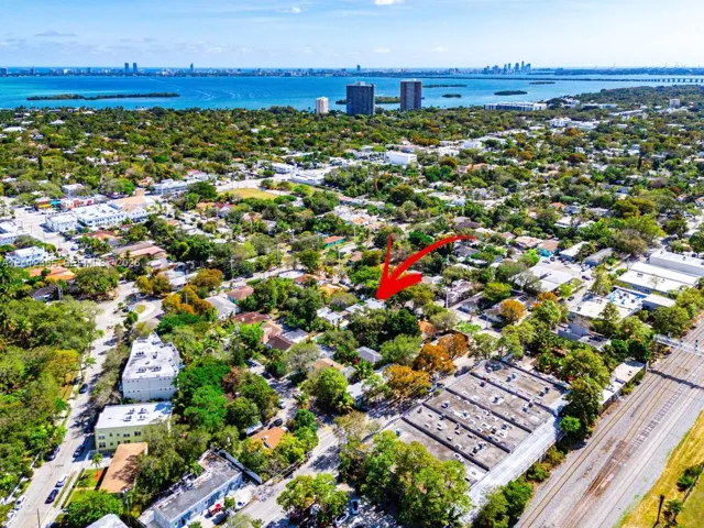 Aerial perspective of a residential lot featuring mature tree canopy, extensive vegetation, and coastal water proximity
