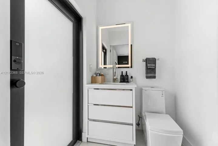 Modern vanity featuring white cabinetry, metallic hardware, and a solid surface countertop