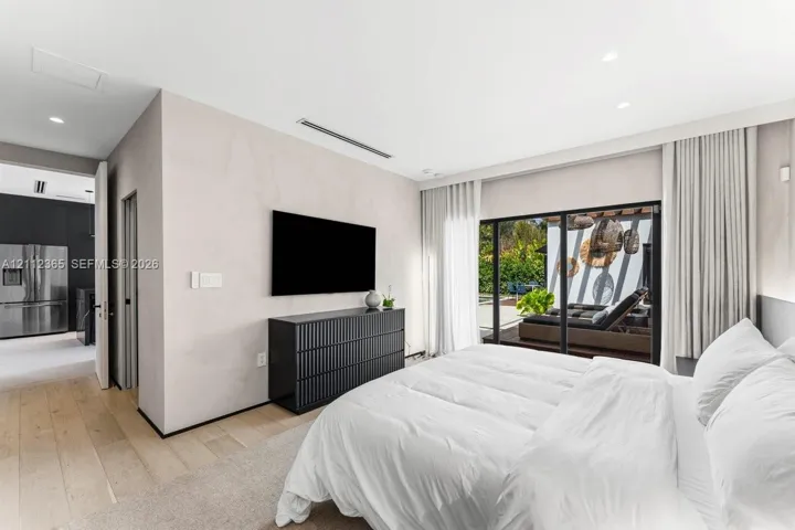 Neutral-toned walls, wood-finish flooring, recessed lighting, and expansive floor-to-ceiling sliding glass doors