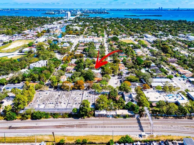 Aerial perspective of the property featuring mature tree canopy, proximity to the coastline, and established neighborhood infrastructure