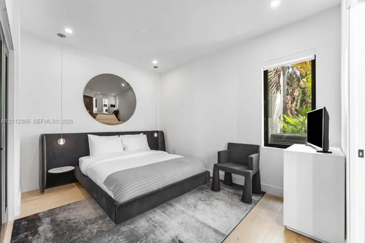 Recessed ceiling lighting, light-toned wood-finish flooring, and a window with exterior greenery