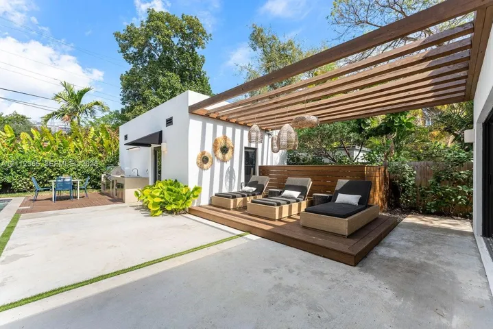Outdoor patio featuring a built-in outdoor kitchen with sink, a raised wood-finish deck, and a wood-slat pergola