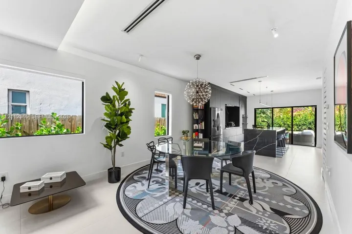 Open-concept interior featuring large-format tile flooring, a kitchen island with dark stone-finish surfacing, recessed lighting, and expansive sliding glass doors