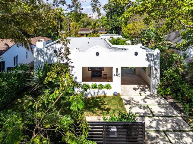 Mission-style architectural exterior with stucco finish, parapet roofline, recessed porch, integrated carport, and geometric paver driveway
