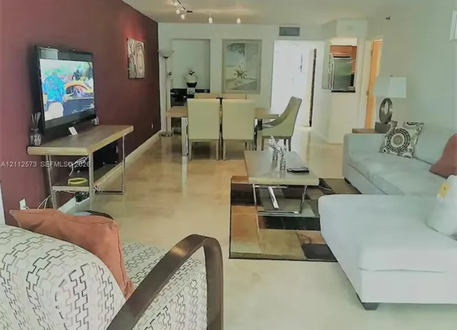 Open-concept interior featuring high-gloss polished stone flooring, a deep-toned accent wall, and recessed wall niches