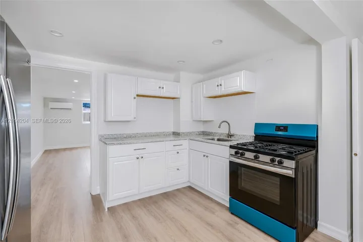 Kitchen featuring white cabinetry, stone-finish countertops, stainless steel gas range, recessed lighting, and wood-finish flooring