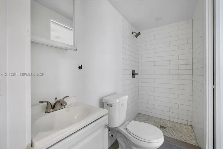 Bathroom featuring a vanity with an integrated sink, polished metal faucet, subway tile shower surround, and mosaic tile shower flooring