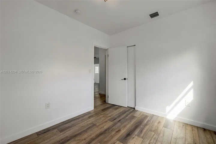 Neutral interior room featuring wood-finish flooring, a solid core swing door, and a closet with a bifold door