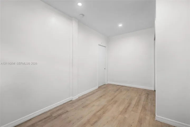 Interior space featuring wood-finish flooring, smooth white walls, and recessed ceiling lighting