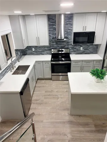 Kitchen featuring shaker-style cabinetry, white solid-surface countertops, a linear-pattern tile backsplash, stainless steel appliances, and a central island