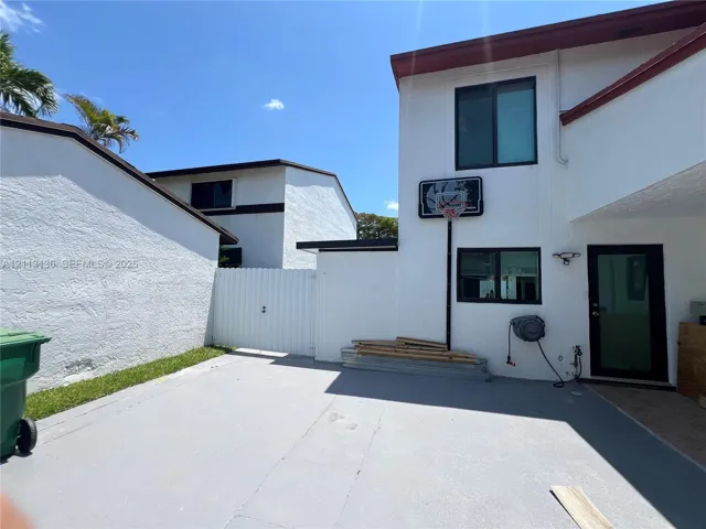 Exterior featuring a textured white stucco facade, a private concrete patio, and gated side access