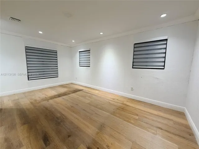 Room featuring wood-finish flooring, recessed lighting, and windows with integrated horizontal blind treatments