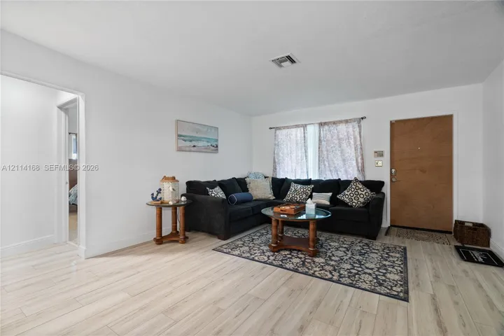Living area featuring neutral wall paint, Italian Tile flooring, and a solid-core entry door