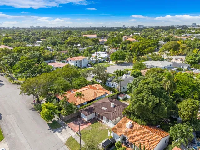 Aerial perspective of a residential neighborhood featuring clay-tiled roofing, paved driveways, manicured lawns, and mature canopy trees