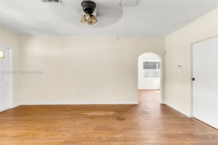 Interior space featuring wood-finish flooring, a neutral wall palette, a ceiling-mounted light fixture, and a rounded architectural archway