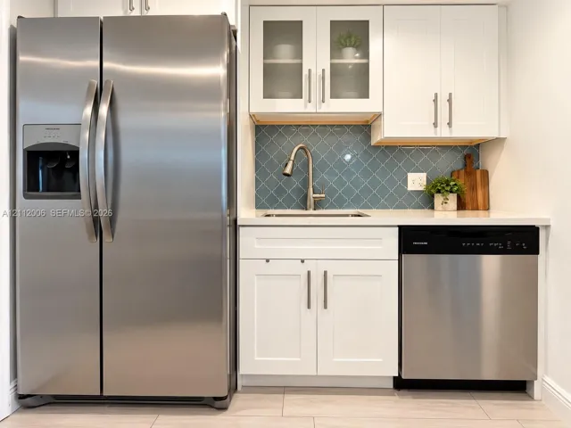 Featuring white Shaker-style cabinetry, stainless steel appliances, blue arabesque tile backsplash and quartz countertops