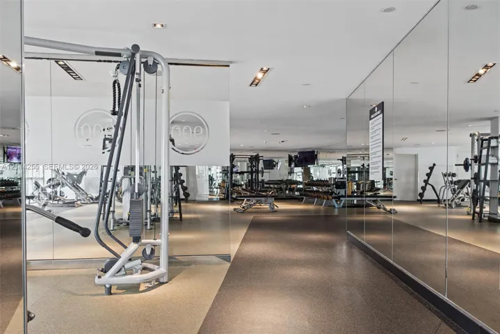 Expansive fitness facility featuring wall-to-wall mirrors, recessed lighting, and durable rubber flooring
