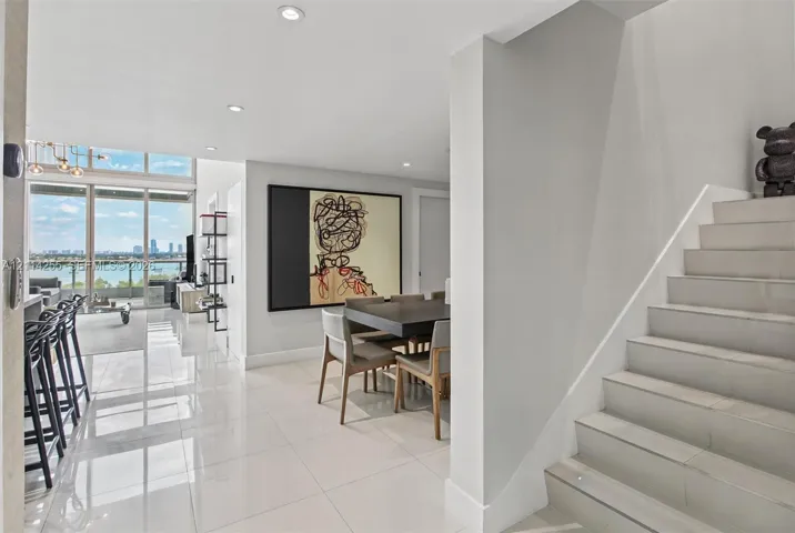 Polished tile flooring, floor-to-ceiling windows with water scenery, recessed lighting, and a staircase with tile treads