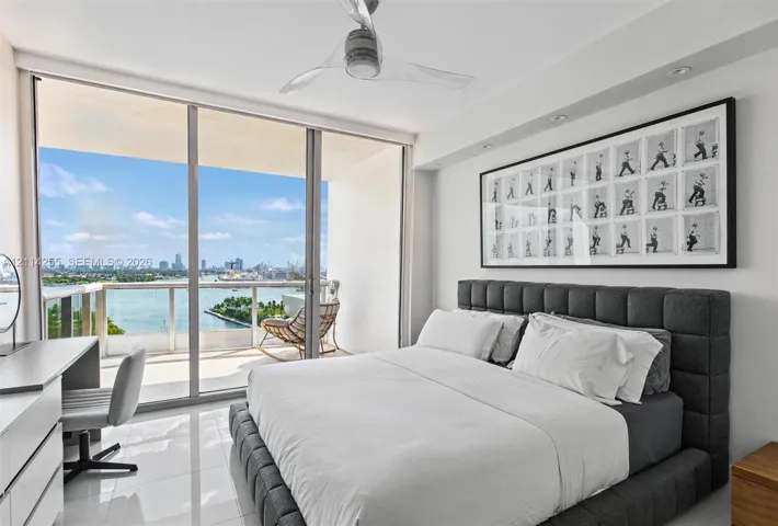 Floor-to-ceiling glass sliding doors, private balcony with glass railing, polished tile flooring, and ceiling fan with integrated lighting