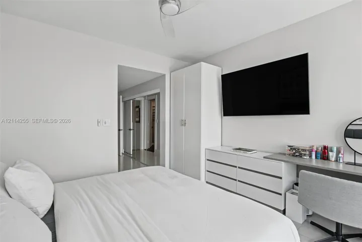 Room interior featuring high-gloss white built-in cabinetry, smooth-finish ceilings with a central fan, and neutral flooring