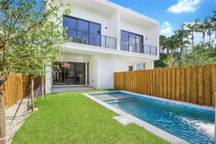 Modern two-story exterior featuring a private swimming pool, fenced backyard, ground-level concrete patio, and a second-story balcony with metal railings