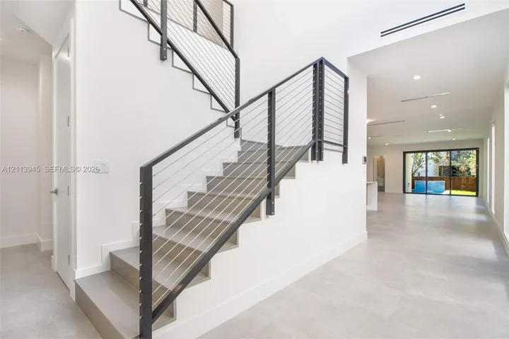 Staircase featuring steel cable railings, large-format tile flooring, and recessed ceiling lighting