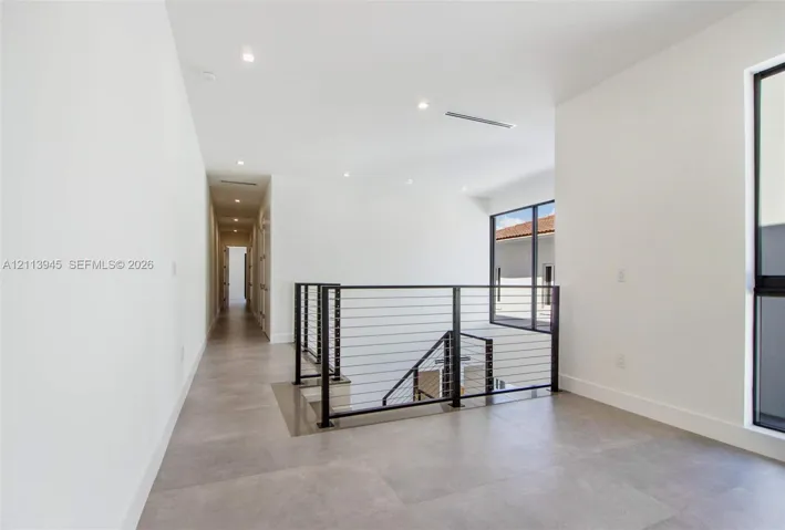 Interior landing featuring large-format tile flooring, metal cable railing, recessed lighting, and expansive windows with black frames