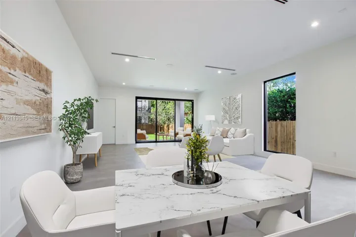 Open-concept interior featuring recessed lighting, large-format tile flooring, oversized floor-to-ceiling windows, and expansive black-framed sliding glass doors