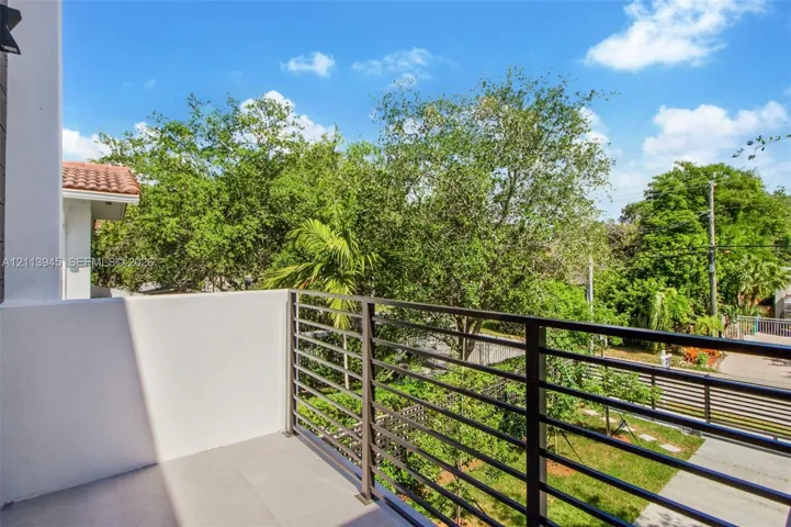 Second-level balcony featuring solid stucco walls, neutral tile flooring, and a horizontal metal railing