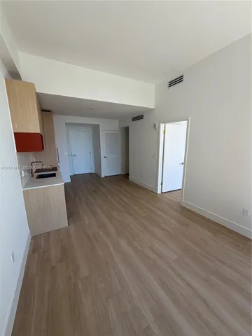 Wood-finish flooring throughout, cabinetry with light wood veneer, solid-surface countertops, and an integrated kitchen sink with a metallic faucet