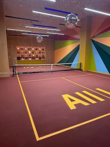 Indoor court featuring a resilient surface, built-in display shelving, decorative wall murals, recessed linear lighting, and suspended spherical reflective fixtures