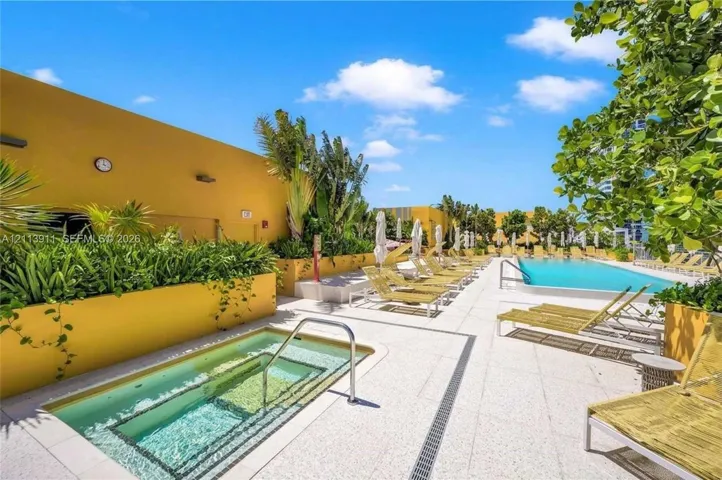 Outdoor terrace featuring an in-ground spa, swimming pool, light-toned stone decking, and integrated raised garden beds