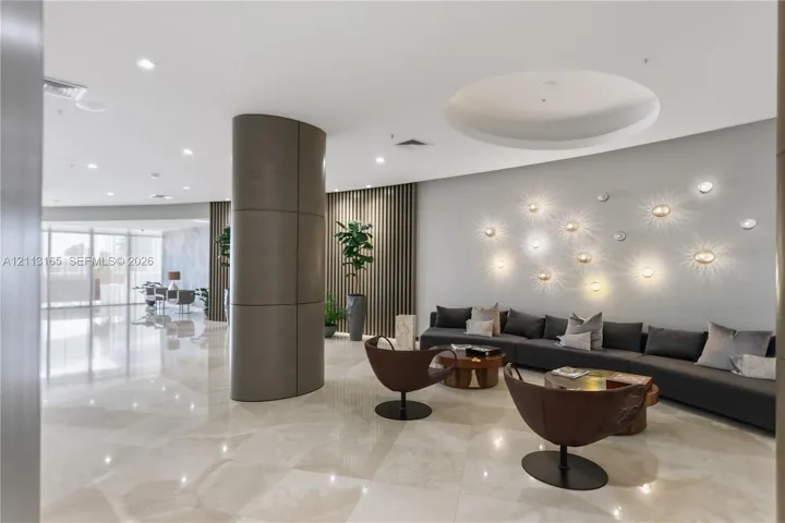 Common area featuring polished stone tile flooring, a curved architectural column, vertical wood-slat wall paneling, and recessed ceiling lighting