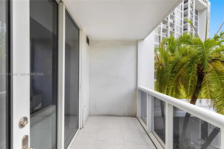 Covered balcony featuring tile flooring, glass panel railings, and floor-to-ceiling sliding glass doors