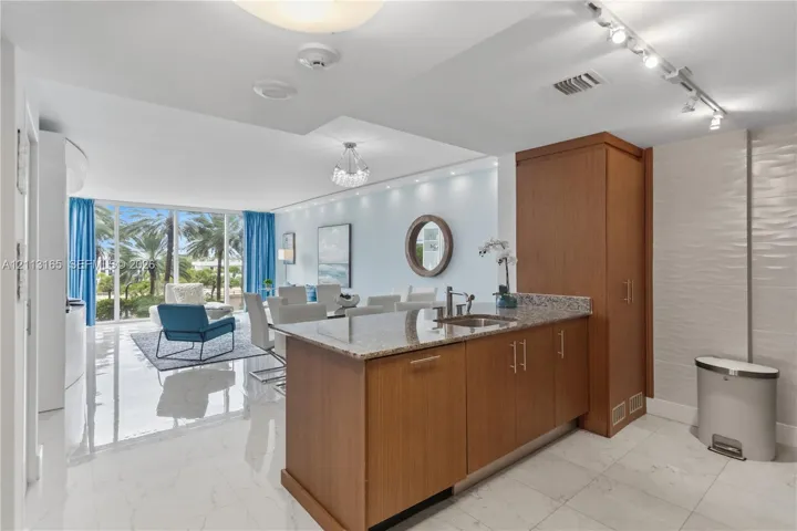 Kitchen featuring wood-finish cabinetry, stone countertops, stainless steel sink, track lighting, and floor-to-ceiling windows