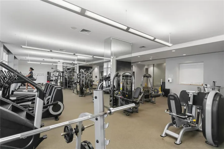 Fitness center featuring linear pendant lighting, expansive mirrors, wall-to-wall carpeting, and recessed ceiling lighting