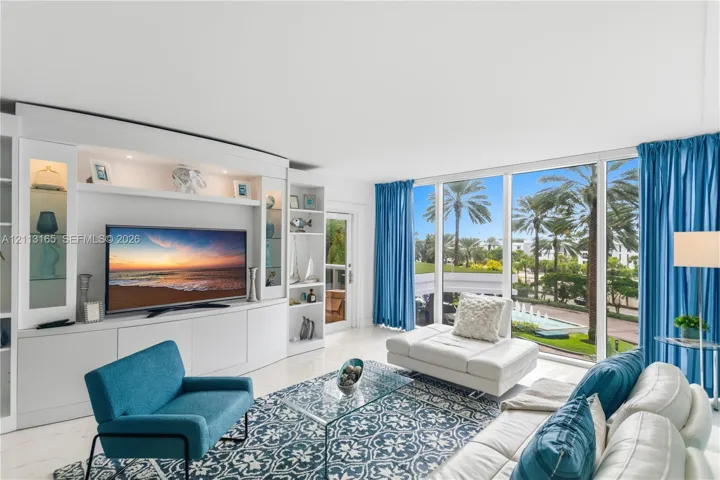 Built-in floor-to-ceiling white cabinetry with integrated display shelving and storage, expansive wall-to-wall glass windows, and polished stone-finish flooring